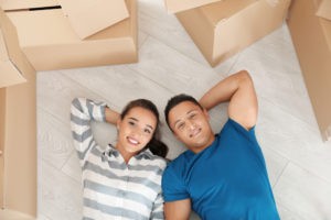 happy young couple lying floor their new apartment near moving boxes