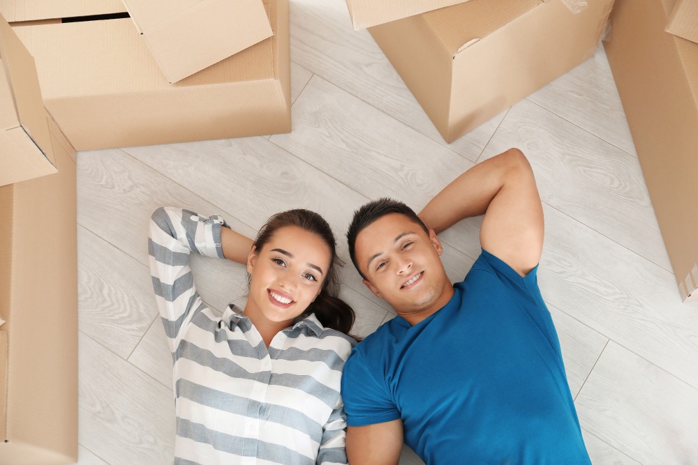 happy young couple lying floor their new apartment near moving boxes