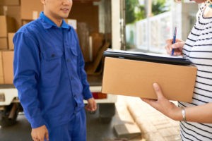 moving house company courier blue uniform looking woman signing delivery service documents