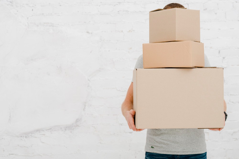 unrecognizable man carrying boxes