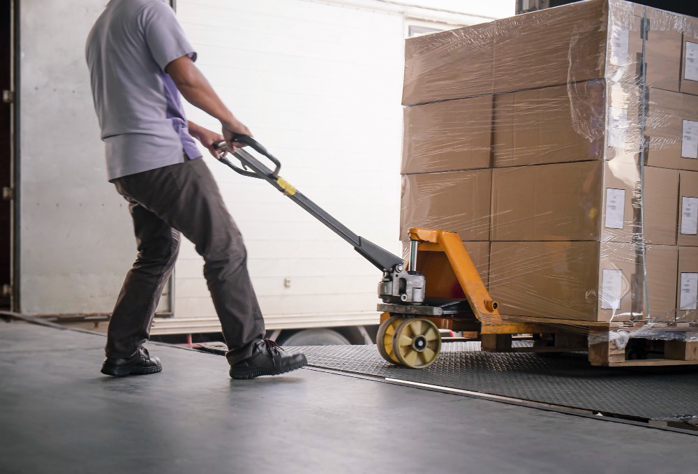 warehouse worker unloading cargo boxes pallet cargo truck parked loading dock warehouse